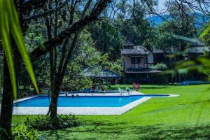 una piscina en un patio con una casa al fondo en CASA DA ILHA em CONDOMINIO, en Ilhabela