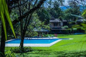 a swimming pool in a yard with a house in the background at CASA DA ILHA em CONDOMINIO in Ilhabela