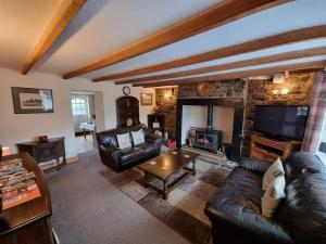 a living room with a leather couch and a fireplace at Low Chesters House in Burtree Ford