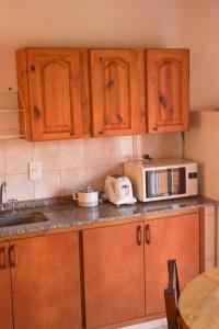 a kitchen with wooden cabinets and a microwave on the counter at Laberinto Gesell in Villa Gesell