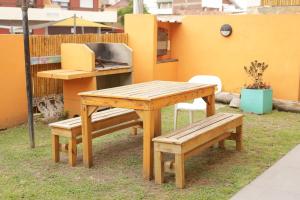 mesa y banco de madera con parrilla, mesa y bancos en Laberinto Gesell, en Villa Gesell