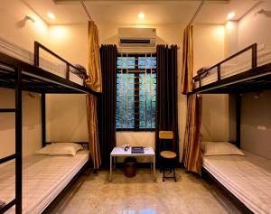 a dorm room with two bunk beds and a table at Ha Giang Ali Hostel in Ha Giang