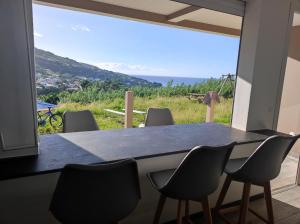une table à manger avec des chaises et une grande fenêtre dans l'établissement Villa NoAmy, à Les Anses-d'Arlet