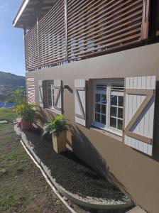 ein Haus mit Fenstern und Pflanzen davor in der Unterkunft Villa NoAmy in Les Anses-dʼArlets