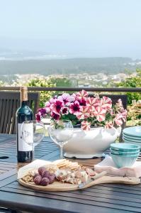 uma mesa com uma taça de flores e uma garrafa de vinho em Casa Bela Vista de Moledo em Moledo