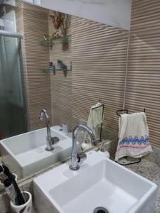 a bathroom sink with two faucets and a mirror at Apartamento Encantador - MAKAMBIRA RESIDENCE in Porto De Galinhas