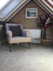 a room with a chair and a table with a vase of flowers at 3 BEDROOM 5* BARN CONVERSION COTSWOLDS in Chipping Norton