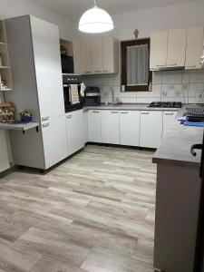 a kitchen with white cabinets and a wooden floor at Casa Sofia in Borsa