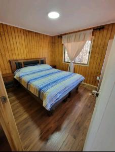 Un dormitorio con una cama con paredes de madera y una ventana en Cabañas Renacer en Casa Grande - Algarrobo, en Algarrobo