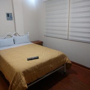 - une télécommande assise sur un lit dans une chambre dans l'établissement Hospedaje, à Quito