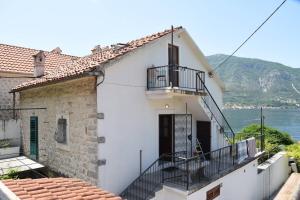a white house with a balcony and a body of water at Mansarda apartment in Kotor