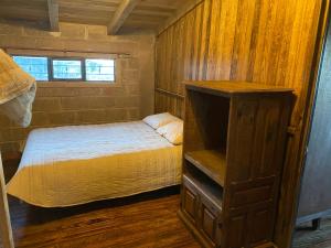 a small bedroom with a bed and a wooden wall at Cabañas Agua del Oyamel in Perote