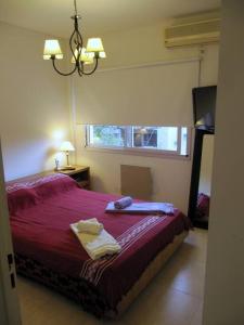 Un dormitorio con una cama roja con toallas. en Nuevo y bonito departamento en Saavedra-CABA en Buenos Aires