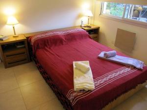 um quarto com uma cama vermelha com duas toalhas em Nuevo y bonito departamento en Saavedra-CABA em Buenos Aires