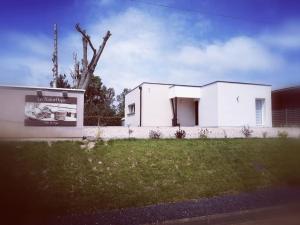 a white building with a sign in the grass at Le NaturOspa in Le Quesnoy-en-Artois