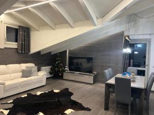 Una sala de estar con un sofá, una mesa y un televisor. en Mansarda Angel's Home, en Ponte di Legno