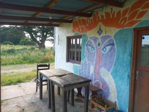 a table in front of a wall with a painting at Casa rural cerca del Cabo in Rincón de los Oliveras