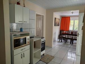 a kitchen with white appliances and a dining room at Casa Brisa do Mar Itapoá conforto à uma quadra da praia in Itapoa