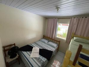 a small bedroom with two beds and a window at Casa Brisa do Mar Itapoá conforto à uma quadra da praia in Itapoa