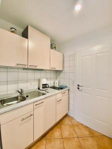 a kitchen with white cabinets and a sink and a door at ADORIS APPARTEMENTS im Lotzbeckpark am See "nachhaltiges Wohnen in Lindau" in Lindau