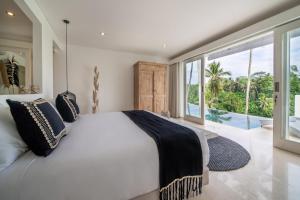 - une chambre avec un lit blanc et une grande fenêtre dans l'établissement Villa Savana Ubud, à Ubud