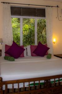 a bed with purple pillows sitting in front of a window at Eco Village Yoga Home in Digana