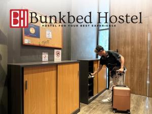 Makkasan的住宿－Bunkbed Hostel，柜台前有手提箱的女人