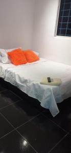 uma cama com lençóis laranja e uma prancha de surf em Hostal-Mirador La Popa em Cartagena de Indias