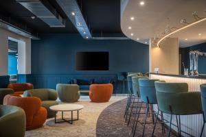 a waiting room with chairs and a flat screen tv at KYRIAD Tours Sud - Ballan Mire in Ballan-Miré