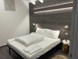 Una cama con sábanas blancas y almohadas en un dormitorio. en Mansarda Angel's Home, en Ponte di Legno
