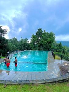 a swimming pool with three people in the water at Eco Village Yoga Home in Digana