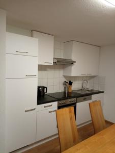 una cucina con mobili bianchi, tavolo e sedie di Johann's Appartements a Kappl