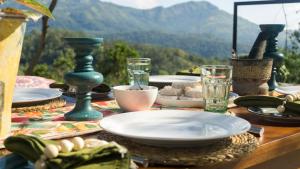 a table with plates and glasses on a table with mountains in the background at Ella Nine Peaks in Ella +146 photos