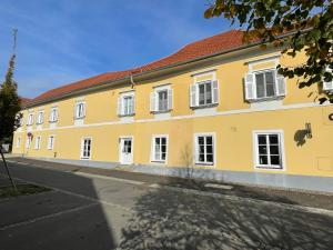 a yellow building with white windows on a street at Ferienwohnungen Sommer in Bad Radkersburg