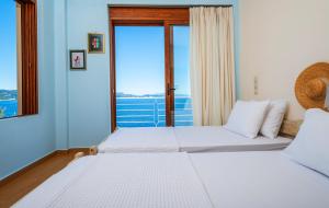 two beds in a room with a large window at Iris Villas Lefkada - Karavi Villa in Évyiros