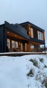 a black house with snow in front of it at Nytt moderne hus på Storsteinnes in Storsteinnes