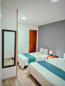 a hotel room with two beds and a mirror at Hotel Maceo 55 - Colonial Inn in Bogotá +28 photos