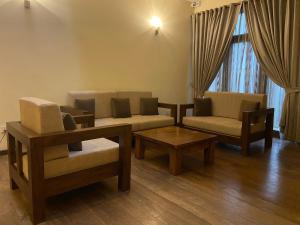 uma sala de estar com duas cadeiras, um sofá e uma mesa em Occazia Residence em Colombo