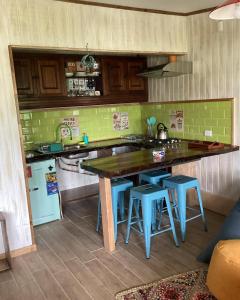 a kitchen with a wooden counter top and blue stools at Departamento La Solar 1 ambiente in Frutillar