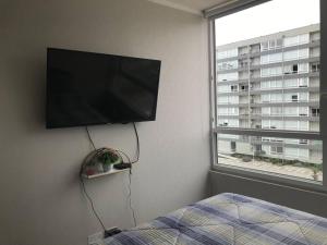 1 dormitorio con TV de pantalla plana en la pared en Dpto Equipado Condonominio Sector Puertas del Mar, en La Serena