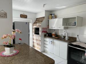 a kitchen with white cabinets and a counter top at Residencial Manauara Torres in Torres