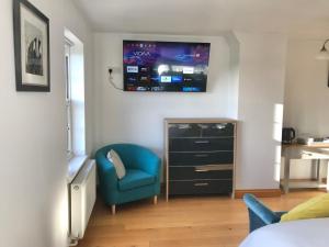 a bedroom with a blue chair and a tv on the wall at Marehay Hall Farm in Belper +22 photos