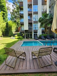 una terraza de madera con 2 sillas y una piscina en Suite House Carilo en Cariló