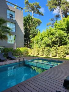 una piscina en un patio trasero con terraza de madera en Suite House Carilo en Cariló