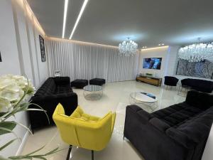 a living room with black couches and yellow chairs at וילה מונטאנו עם בריכה מחוממת וג'קוזי במרכז העיר - Villa Montano with a heated pool and jacuzzi in the city center in Rishon LeẔiyyon