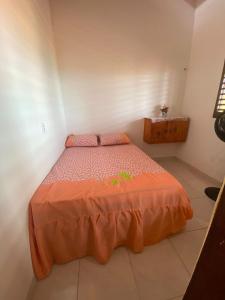 a bedroom with a bed with an orange comforter at Chalé da Kikia in Icapuí