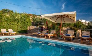 a swimming pool with chairs and an umbrella at Iris Villas Lefkada - Marine Villa in Évyiros