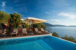 a pool with chairs and an umbrella next to the water at Iris Villas Lefkada - Marine Villa in Évyiros