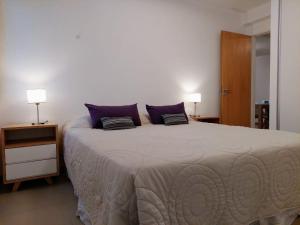 - une chambre avec un grand lit et des oreillers violets dans l'établissement Amanecer en el Lago, à San Carlos de Bariloche