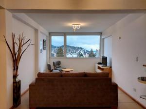 - un salon avec un canapé et une grande fenêtre dans l'établissement Amanecer en el Lago, à San Carlos de Bariloche